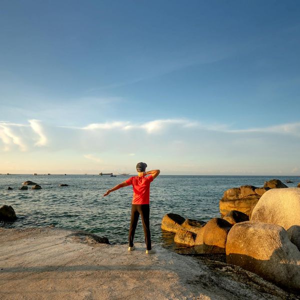 Silhouette of a man stretching during sunrise, symbolizing well-being and energy.
